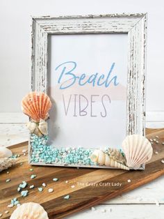 an old frame with shells and sea glass in front of it that says beach vibes