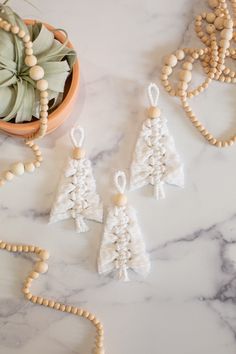 crocheted ornaments and beads on a marble table with a potted plant in the background