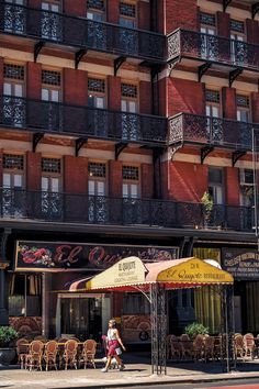 the building has many windows and balconies on it's sides, along with tables and chairs