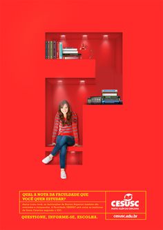 a woman sitting on top of a red shelf in front of a bookcase filled with books