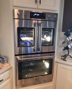 two ovens are built into the wall in this kitchen with white cabinets and stainless steel appliances