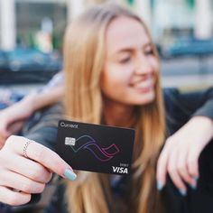 a woman holding up a visa card in her hand