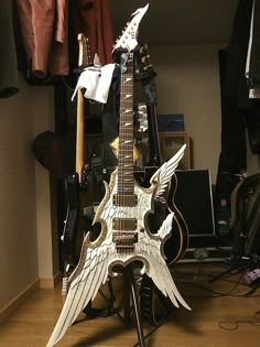 an electric guitar with wings sitting on top of a stand