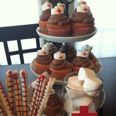 cupcakes and marshmallows are arranged on three tiered trays