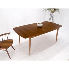 a wooden table with two chairs next to it and a vase on the table top