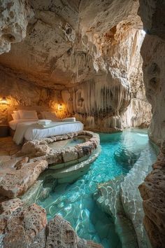 a bed sitting in the middle of a cave next to a pool filled with water