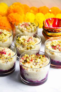 there are many desserts in small glass cups on the table with flowers around them