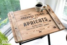 a wooden sign sitting on top of a table next to a coffee cup and plant