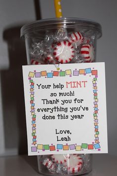 a jar filled with candy canes sitting on top of a table next to a sign