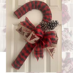 a red and black plaid christmas wreath with pine cones on the front door hanger