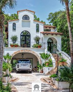 a truck is parked in front of a house with palm trees and potted plants