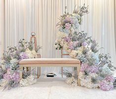 an arrangement of flowers and greenery on display at a wedding ceremony in front of a white backdrop