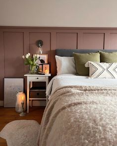 a bedroom with a bed, nightstand and flowers on the side table next to it