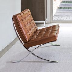 a brown leather chair sitting on top of a white carpeted floor next to a window