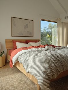 a large bed sitting in a bedroom next to a window with an orange blanket on top of it