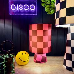 a table topped with two lamps next to a yellow smiley face vase and potted plant