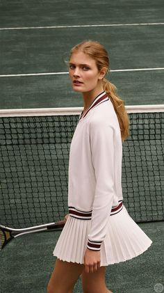 a woman walking on a tennis court with a racquet in her hand,