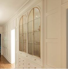 an empty room with wooden floors and white cabinets in the center, along with hardwood flooring