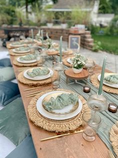 a long table with plates and place settings on it is set for an outdoor dinner