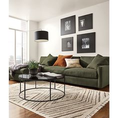 a living room with green couches and pictures on the wall above it's coffee table