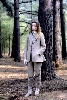 a woman standing next to a tree in a forest wearing tights and boots with knee high socks