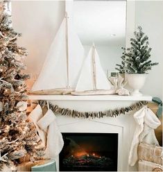 a decorated christmas tree in front of a fire place with a sailboat on top