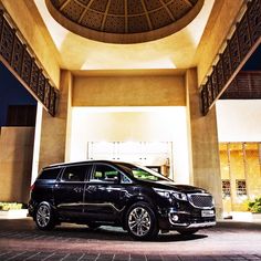 a black minivan parked in front of a building with a dome ceiling above it