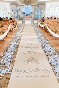 the aisle is decorated with blue flowers and white ribbon for guests to sit down at