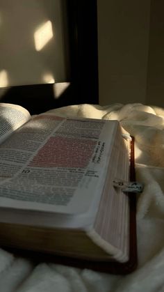 an open book sitting on top of a bed