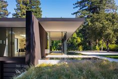 a modern house in the middle of a park with grass and trees on both sides