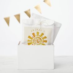 a small white box with a yellow and white gift bag in it on a table