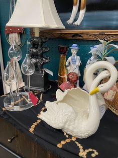 a white swan figurine sitting on top of a table next to a lamp