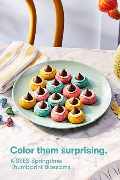 a plate full of colorful cupcakes sitting on top of a table