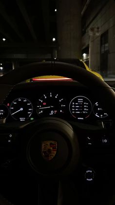 the dashboard of a sports car at night in a parking garage with its lights on