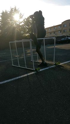 a person riding a skateboard on the side of a road next to a fence