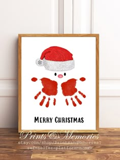 a christmas card with a santa hat on it and two hands in the shape of a handprint