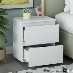 a white night stand with two drawers and a plant on top in a bedroom next to a bed