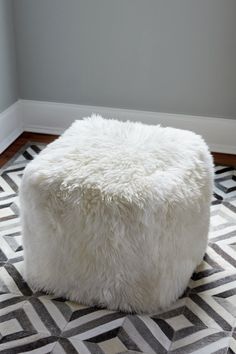 a white ottoman sitting on top of a black and white rug