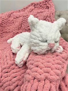 a white teddy bear laying on top of a pink blanket