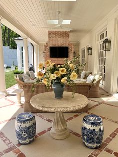 a vase with yellow flowers sitting on top of a table next to two blue and white urns