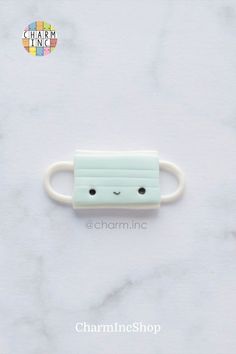 a small white ring with a face drawn on it's side and the words charm inc above it