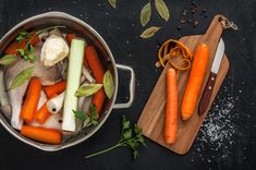 carrots, celery and onions in a pot on a wooden cutting board