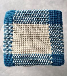 a blue and white crocheted bag hanging from a hook