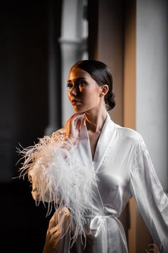 a woman wearing a white robe with feathers on it