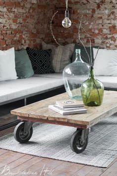 a living room with a couch, coffee table and glass vase on the wheels in front of it