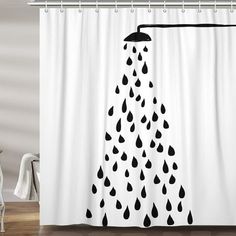 a shower curtain with black and white rain drops hanging from it's side on a wooden floor