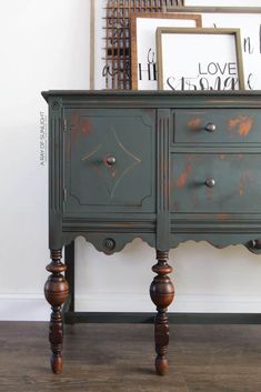 an old dresser is painted green and has some wood knobs on the top, along with two framed pictures