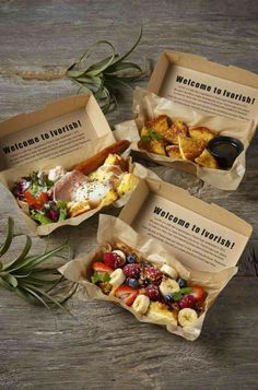 three boxes filled with food sitting on top of a wooden table