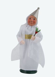 a small doll dressed in white holding a red rose and wearing a silver hat with gold trim