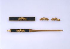 three different types of gold and black items on a white surface, including a pair of scissors